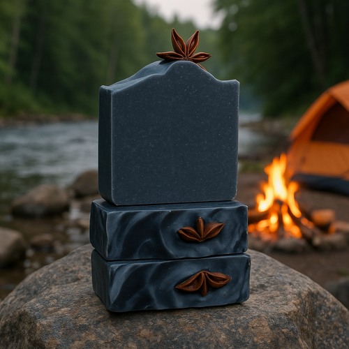 Blue soap bars on rock with tent positioned next to campfire at riverside campsite